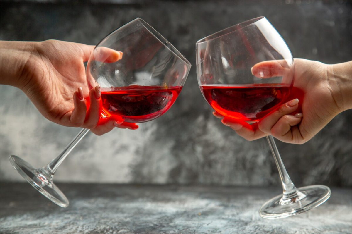 Почему после красного вина. Фото рука держит бокал с вином.